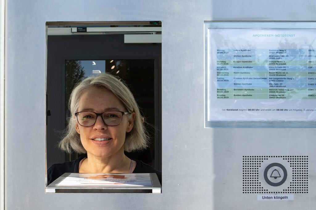 Apothekenmitarbeiterin guckt durch die geöffnete Notdienstklappe